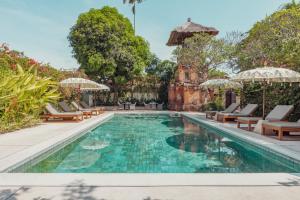 una imagen de una piscina con sillas y sombrillas en The Pavilions Bali, en Sanur