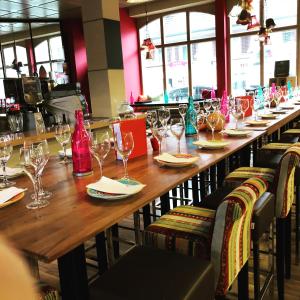 una larga mesa de madera en un restaurante con copas de vino en SASS APARTHOTEL, en Schönenwerd