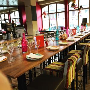 a long wooden table in a restaurant with wine glasses at SASS APARTHOTEL in Schönenwerd