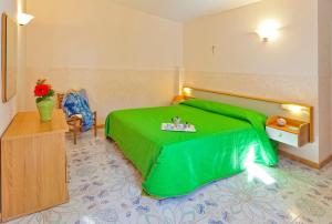 a bedroom with a green bed with a table on it at Casa Vacanze Parco Del Generale in Ischia