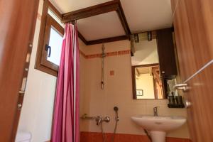 a bathroom with a sink and a pink shower curtain at AnnaDes Apartments & Studios Chios in Karfas +185 photos
