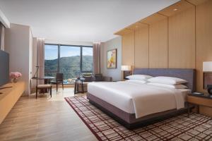 a bedroom with a large white bed and a desk at Hyatt Regency Hengqin in Zhuhai
