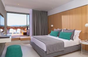 a bedroom with a large bed with green pillows at Skiathos Palace Hotel in Koukounaries