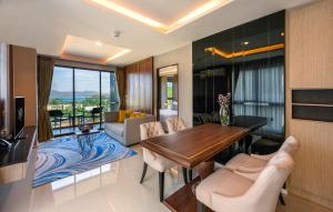 a living room with a wooden table and chairs at Mida Grande Resort Phuket Official Account in Surin Beach