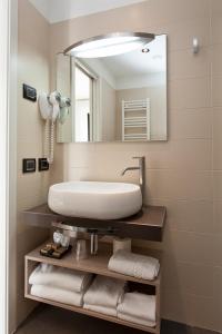 a bathroom with a sink and a mirror and towels at Hotel Adlon in Lido di Jesolo