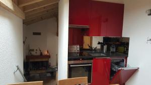 eine Küche mit roten Schränken und einer Arbeitsplatte in der Unterkunft Les Combles des Murailles in Champéry