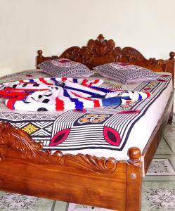 a wooden bed with a colorful quilt on it at Lakshan View Resort in Haputale
