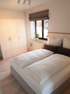 duże białe łóżko w pokoju z oknem w obiekcie Ferienwohnungen am Danewerk w mieście Dannewerk
