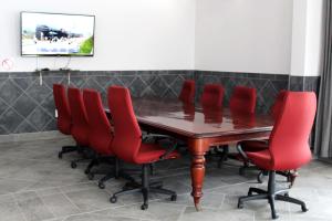 a conference room with a wooden table and red chairs at Lodge @ Leadwood in Boksburg