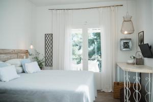 a white bedroom with a bed and a window at Odyssey Suites in Poros