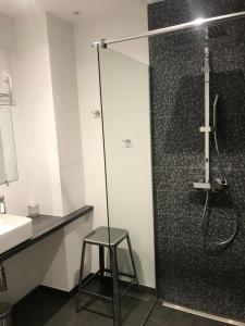 a bathroom with a shower with a stool next to a sink at Augustodun'Home in Autun