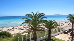 a view of a beach with palm trees and the ocean at Aparthotel Ses Fotges in Playa de Muro