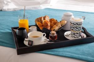 ポルティシオにあるHotel le Jardin d'Emileのベッドの上にコーヒーとペストリーを用意した朝食トレイ