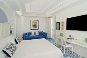 a white bedroom with a large bed and a tv at Piazzetta Diefenbach in Capri