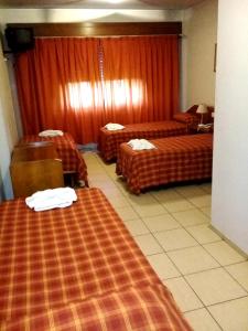 una habitación de hotel con 2 camas y cortinas rojas en Hotel El Torreon en Mendoza