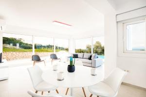 a white living room with a white table and chairs at Villa Arete by PosarelliVillas in Perítheia