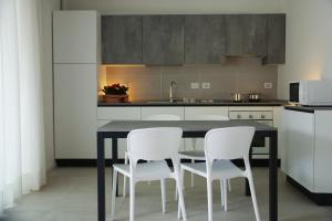 a kitchen with a table and two white chairs at Cala Blu Residence con piscina-Centralissimo Lido di Jesolo in Lido di Jesolo