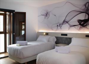 two beds in a hotel room with a painting on the wall at Hotel NERU con Encanto in León