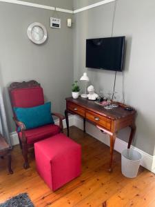 a living room with a tv and a chair and a table at Casa Mia in Pietermaritzburg