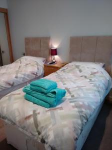 a bed with two green towels sitting on it at Strachan House in Inverkeithing