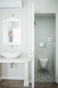 a white bathroom with a sink and a toilet at Odyssey Suites in Poros