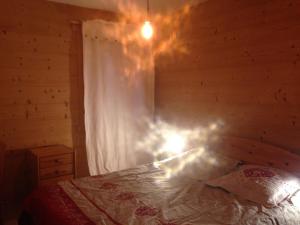 1 dormitorio con 1 cama con ventana y lámpara de araña en La Vardase en Le Grand-Bornand