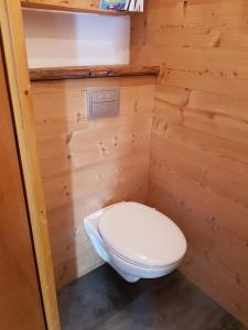 La salle de bains est pourvue de toilettes blanches et d'un mur en bois. dans l'établissement La Vardase, au Grand-Bornand