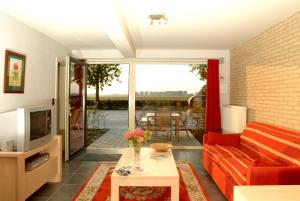 un soggiorno con divano rosso e TV di Holiday Home De Colve a Bruges