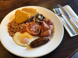 a white plate topped with eggs, sausage, beans and bacon at Castle Inn by Greene King Inns in Bakewell