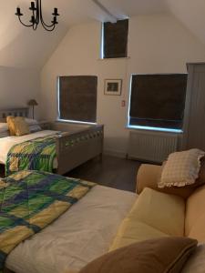 a bedroom with two beds and a couch and two windows at Appletree Cottages in Mildenhall