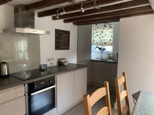 uma cozinha com armários brancos e uma mesa com cadeiras em Appletree Cottages em Mildenhall