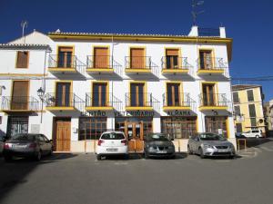 un bâtiment blanc avec des voitures garées devant lui dans l'établissement Apartamento Terranova Esquina Placeta, à Alhama de Granada