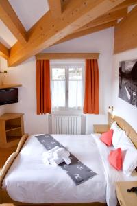 a bedroom with a large white bed with orange curtains at Al Piccolo Hotel in Vigo di Fassa