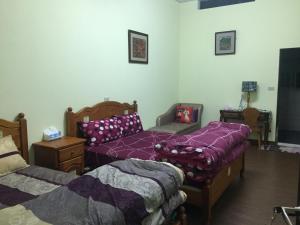 GO Bill B&B في Xinyi: سريرين في غرفة ذات أغطية أرجوانية