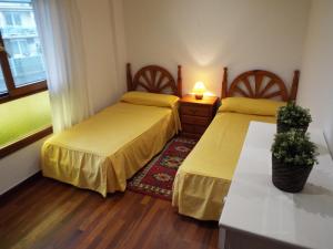 a bedroom with two beds and a table with a lamp at Casa de campo cerca del mar in Miengo