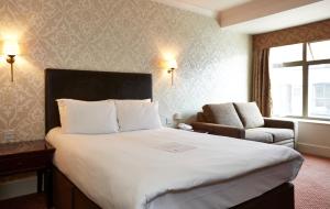 a hotel room with a large bed and a chair at Ye Olde Talbot Hotel by Greene King Inns in Worcester