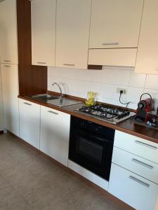 a kitchen with white cabinets and a black stove top oven at Bicocca Flat A in Milan