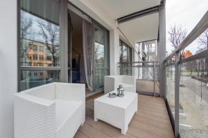 balcón con muebles blancos y ventanas grandes en Apartamenty Sun & Snow Riverfront Gdańsk, en Gdansk