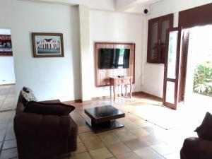 a living room with a couch and a tv at Casa Siroba beira rio para 10 P in Morretes
