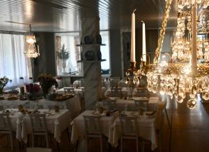 ein Esszimmer mit weißen Tischen und Kronleuchtern in der Unterkunft Hotel Villa Maria & Apartment in Varraze