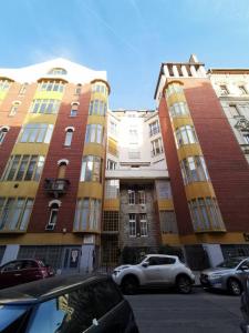 two tall buildings with cars parked in front of them at High Sky Apartment in Budapest