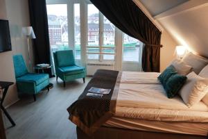 a bedroom with a bed and two chairs and a window at Clarion Collection Hotel Skagen Brygge in Stavanger