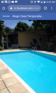 una piscina azul junto a un edificio en Casa Parada Modelo en Guapimirim
