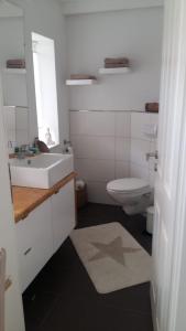 a white bathroom with a sink and a toilet at Huus Utspann in Tönning