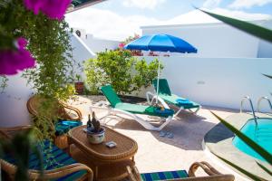 een patio met stoelen, een parasol en een tafel bij ALIZUTH VILLA in Puerto del Carmen