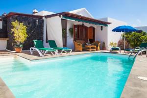 een zwembad met stoelen en een huis bij ALIZUTH VILLA in Puerto del Carmen