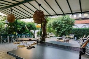 a ping pong table on a patio with tables and chairs at Hotel Villa Maria & Apartment in Varazze