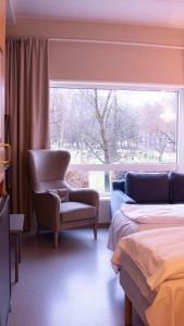 a bedroom with a chair and a large window at Ullevål Hotel in Oslo
