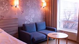 Ullevål Hotel في أوسلو: غرفة بها أريكة زرقاء وطاولة ونافذة