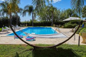 a hammock and chairs in front of a pool at Scent Selinunte Garden in Castelvetrano Selinunte +12 photos
